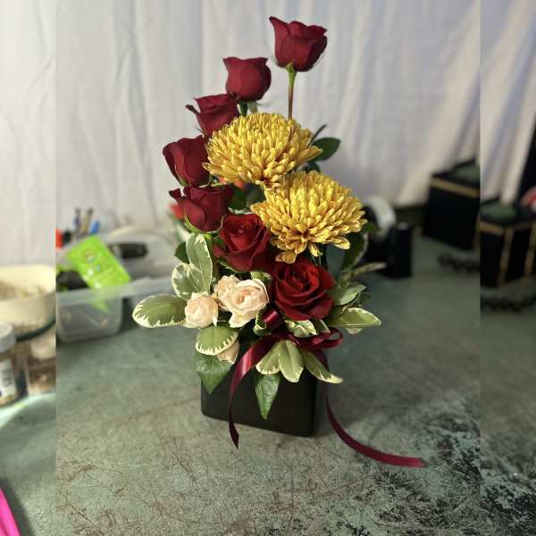 Arrangement of red roses and yellow chrysanthemums in a black box