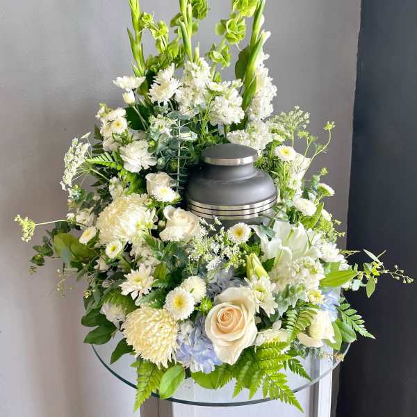 White floral funeral arrangement with a gray urn centerpiece