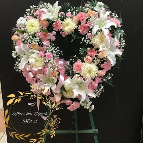 Heart-shaped floral wreath with pink and white flowers on an easel