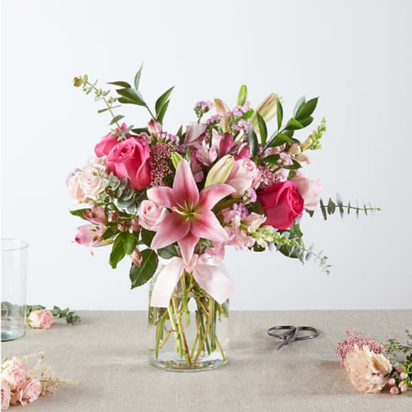 Pink and white bouquet with lilies and roses in a clear glass vase