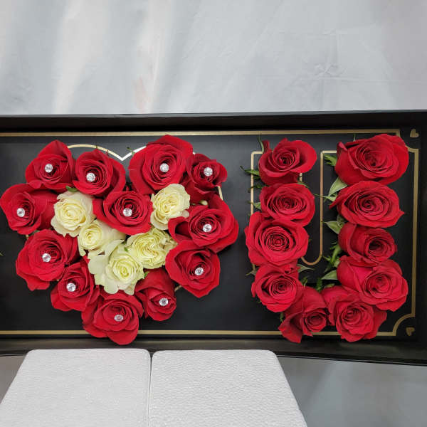 Red and white roses arranged in a black display box spelling "MOM"