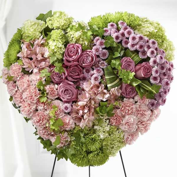 Heart-shaped floral arrangement with pink roses, carnations, and green blooms