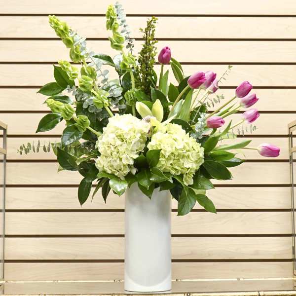 Pink tulips and pale green hydrangeas in a white vase