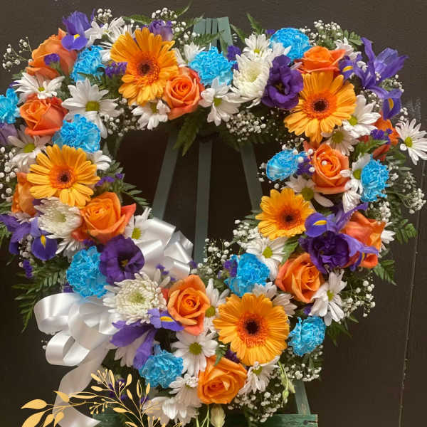 Heart-shaped floral wreath with orange roses, gerbera daisies, and blue carnations