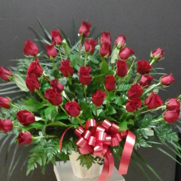 Large bouquet of red roses with a red ribbon bow in a white vase