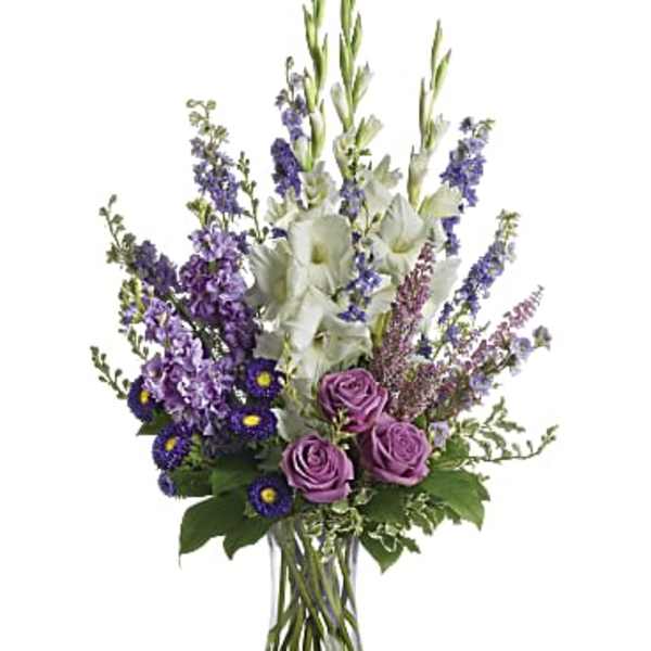 Tall bouquet of purple and white flowers in a clear glass vase