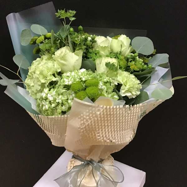 Green and white bouquet wrapped in beige paper with a ribbon