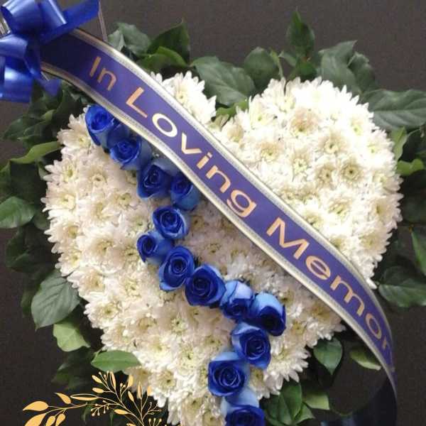 Heart-shaped white flower arrangement with blue roses and a ribbon