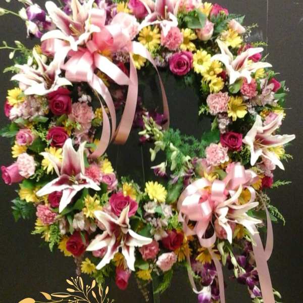Heart-shaped floral wreath with pink lilies, roses, and ribbons