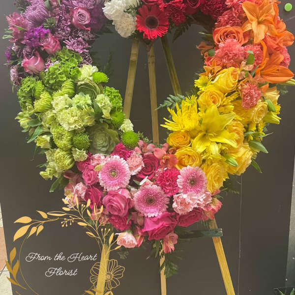 Heart-shaped floral wreath in rainbow colors on an easel