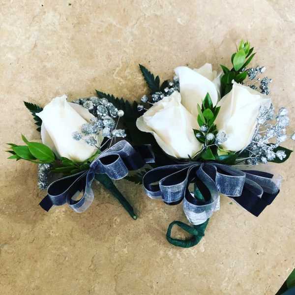 Pair of white rose boutonnieres with silver baby's breath and dark ribbon bows