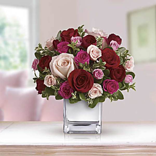Bouquet of red, pink, and white roses in a clear glass vase