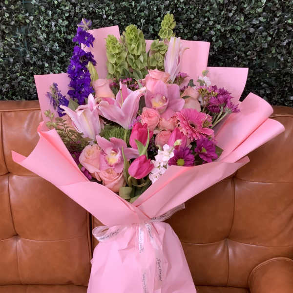 Pink bouquet with lilies, roses, and purple flowers wrapped in pink paper