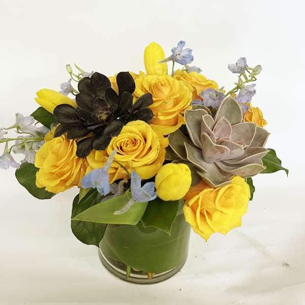 Yellow roses and succulents arranged in a glass vase