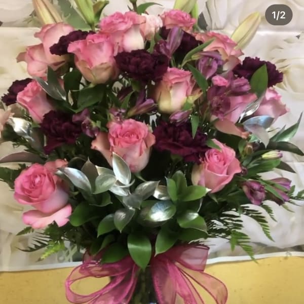 Bouquet of pink roses and dark purple flowers tied with a pink ribbon