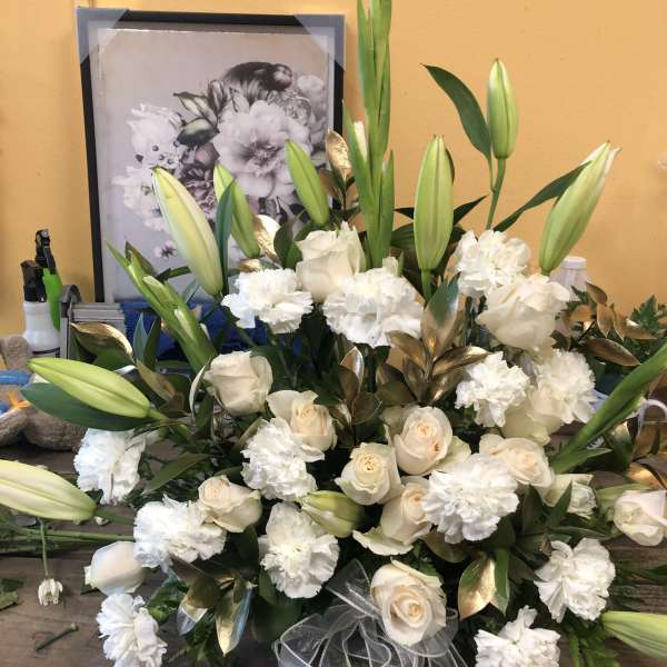 White roses and lilies arranged with carnations and ribbon
