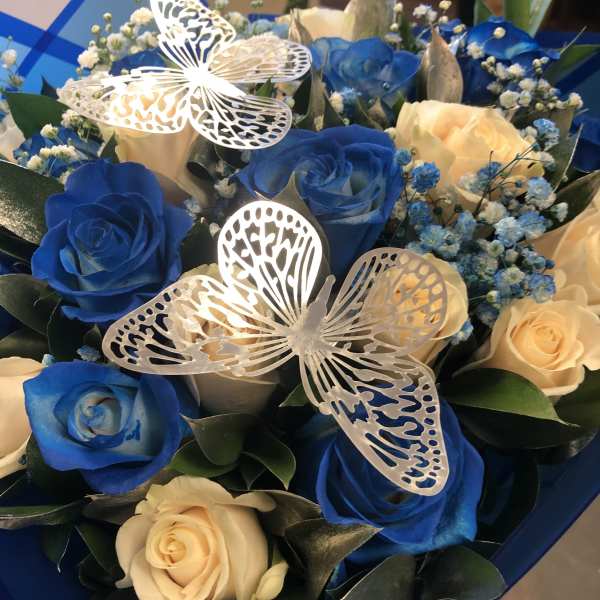 Blue and cream roses with butterfly decorations in a bouquet