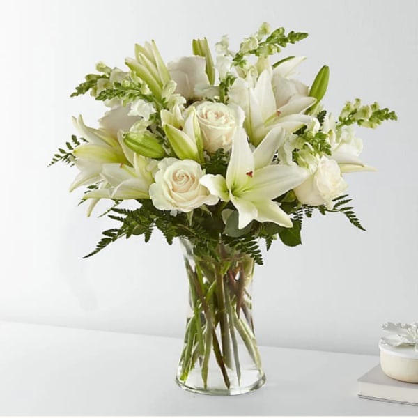 White lilies and roses arranged in a clear glass vase