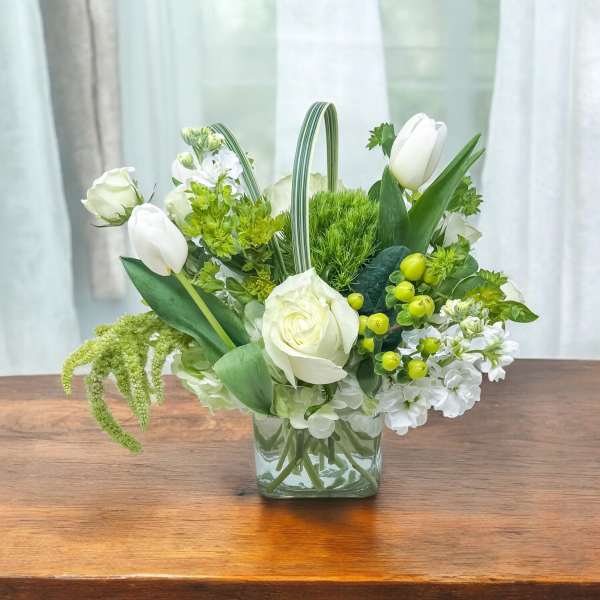 White tulips and roses arranged in a clear glass vase