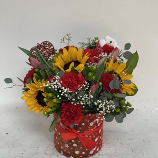 Bouquet of sunflowers and red carnations in a red patterned box