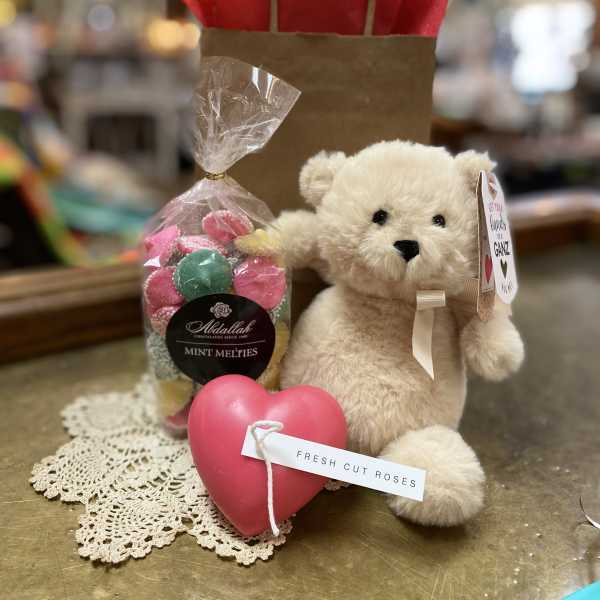 Gift set with teddy bear, bag of candies, and pink heart on a lace doily