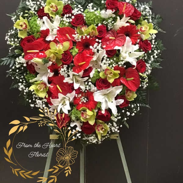 Heart-shaped floral spray with red, white, and green flowers on an easel