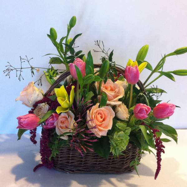 Basket arrangement of pink and peach roses with tulips and lilies