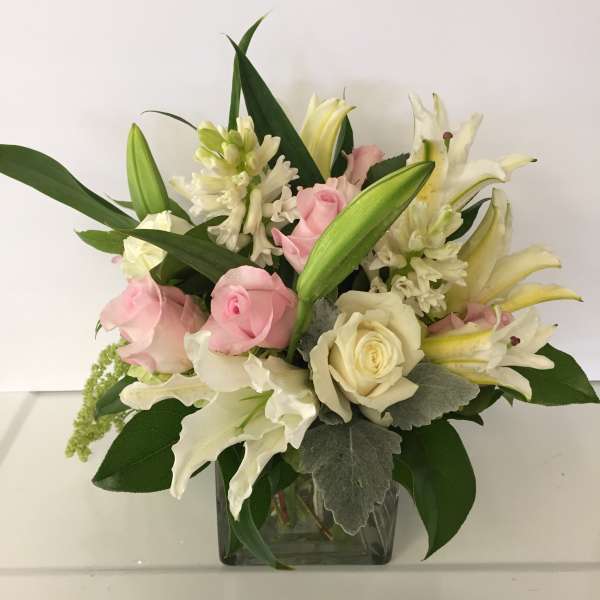 Pink and white roses with lilies in a glass vase