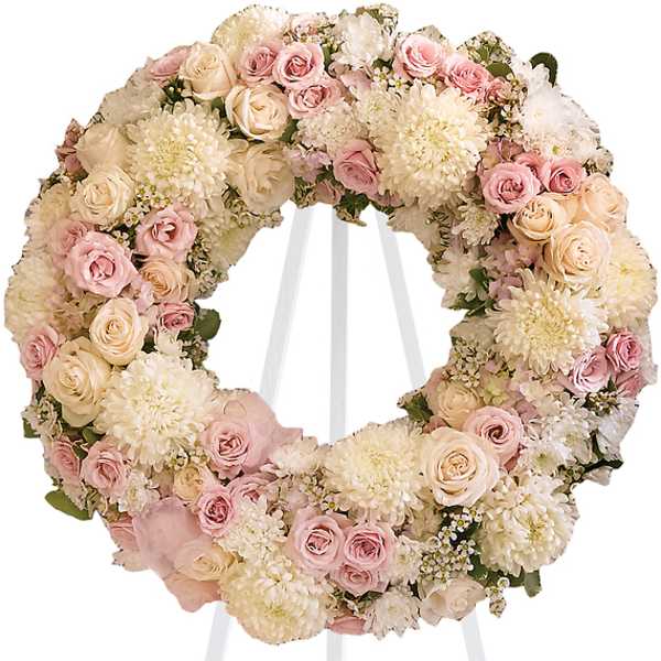 Pastel floral wreath on a white stand with pink and cream blooms