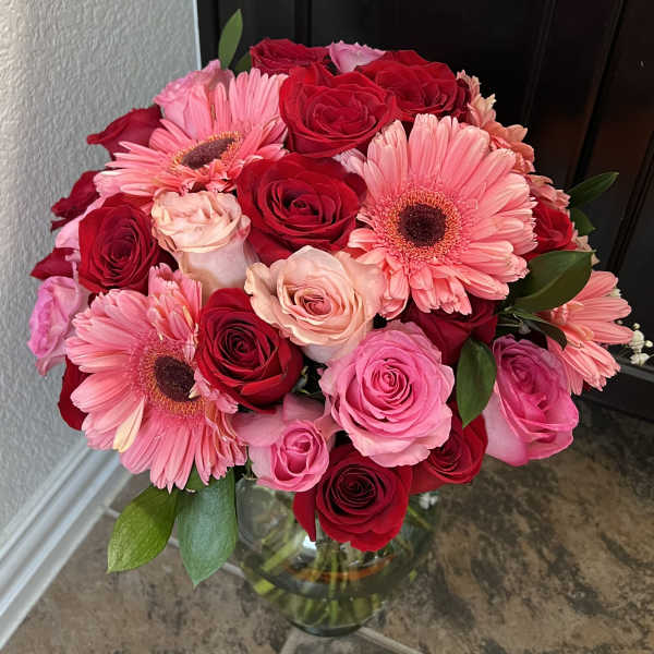 Bouquet of pink gerbera daisies and red roses in a glass vase
