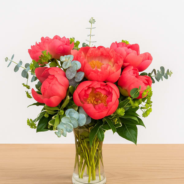 Pink peonies in a clear glass vase with eucalyptus