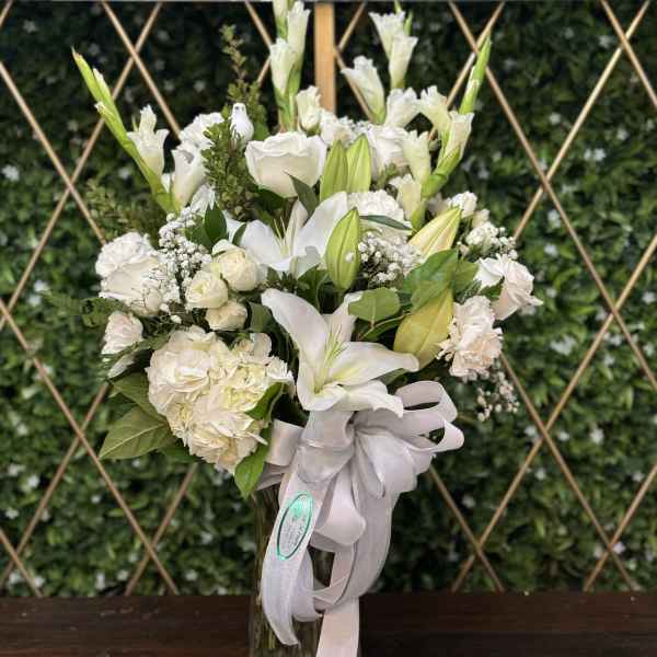 White floral bouquet in a glass vase with a pale ribbon