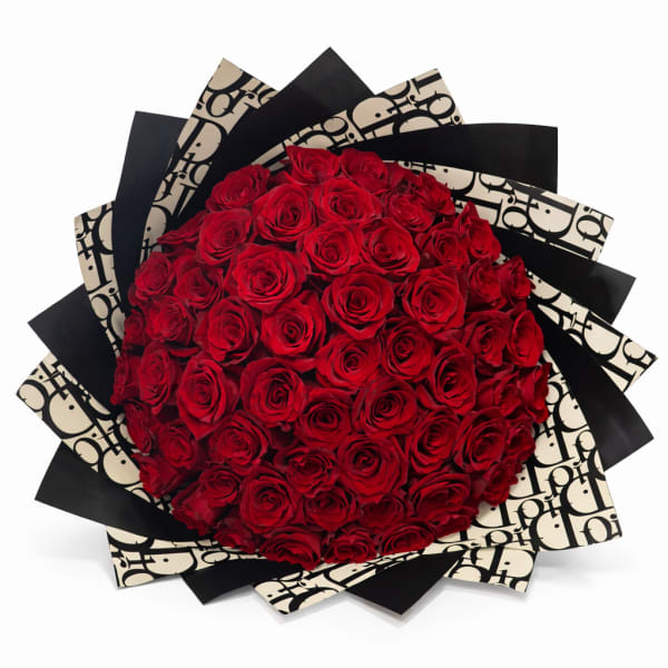 Large round bouquet of red roses wrapped in layered black and cream patterned paper