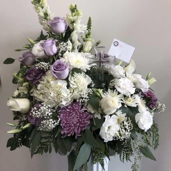 Large floral spray with white and lavender flowers and a clear cross centerpiece