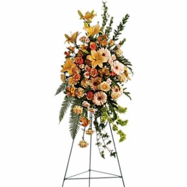 Tall standing spray of peach and yellow flowers on a metal easel.
