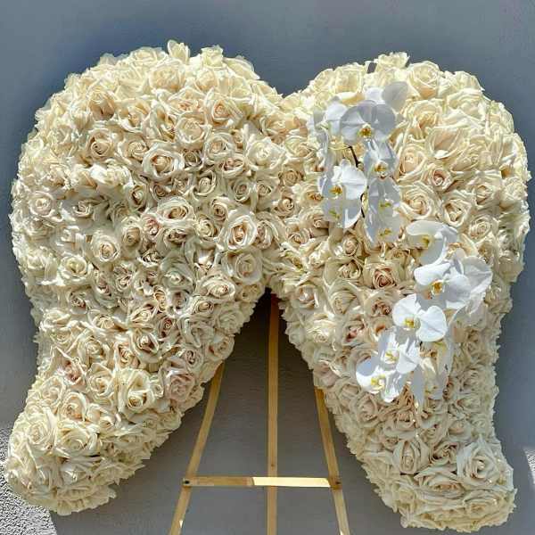 Heart-shaped floral tribute of cream roses with white orchids on an easel