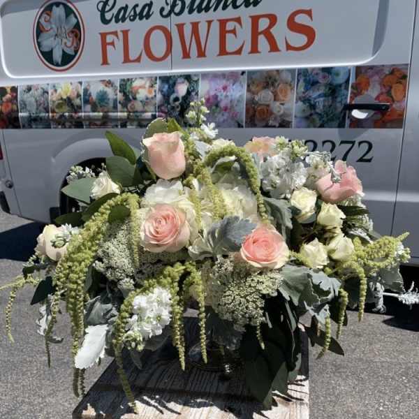 Large bouquet of pale pink and white roses with greenery on a table