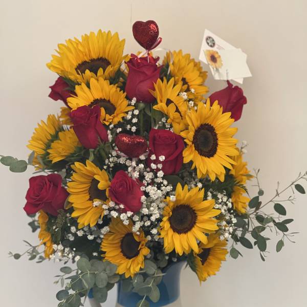 Bouquet of sunflowers and red roses in a painted ceramic pitcher
