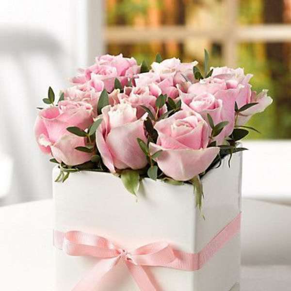 Pink roses arranged in a white box with a pink ribbon