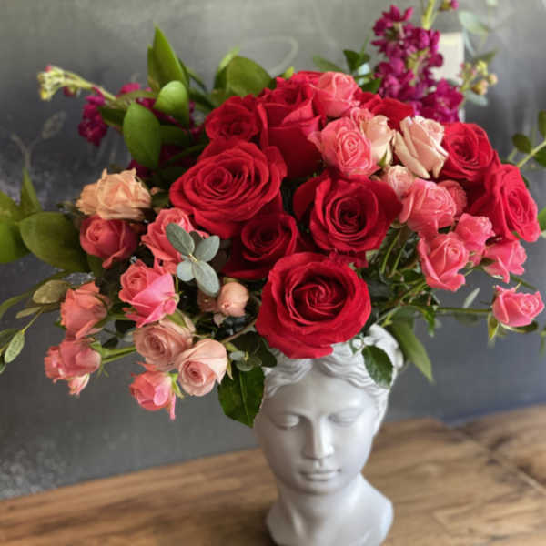 Bouquet of red and pink roses in a white bust vase