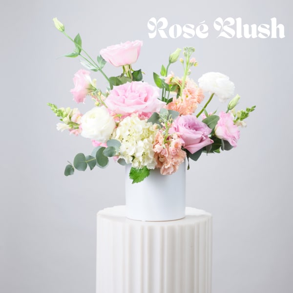 Pink and white roses arranged in a white vase