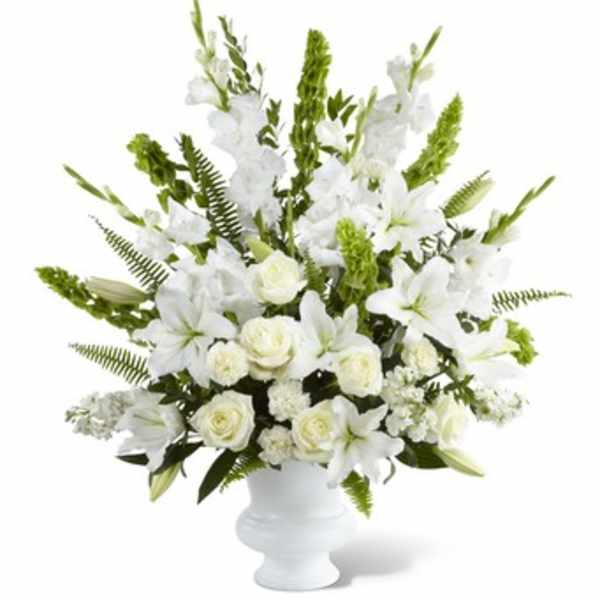 White floral arrangement in a white urn vase