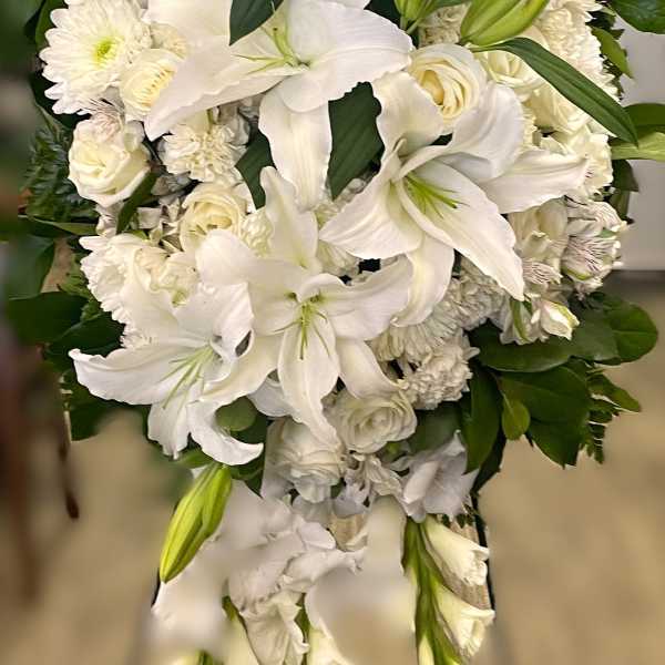 White lily and rose funeral spray with trailing blooms