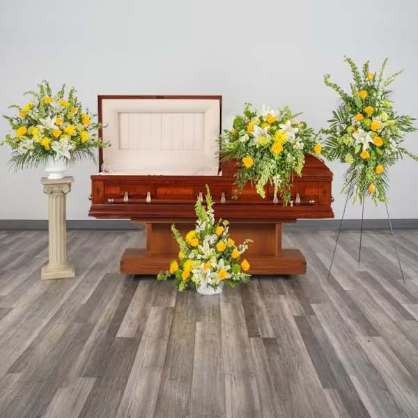 Set of yellow and white funeral floral arrangements around an open wooden casket