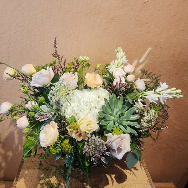Mixed bouquet with pale roses, white blooms, and a succulent centerpiece