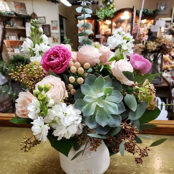 Mixed pink and white flowers in a white vase with succulents