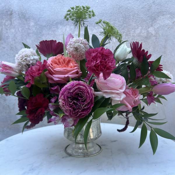 Pink and burgundy mixed flower arrangement in a silver vase
