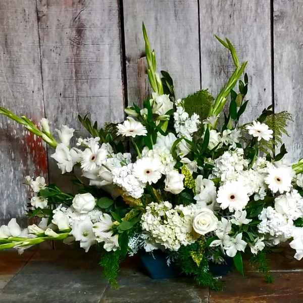 Large white floral arrangement with long green spikes in a low container