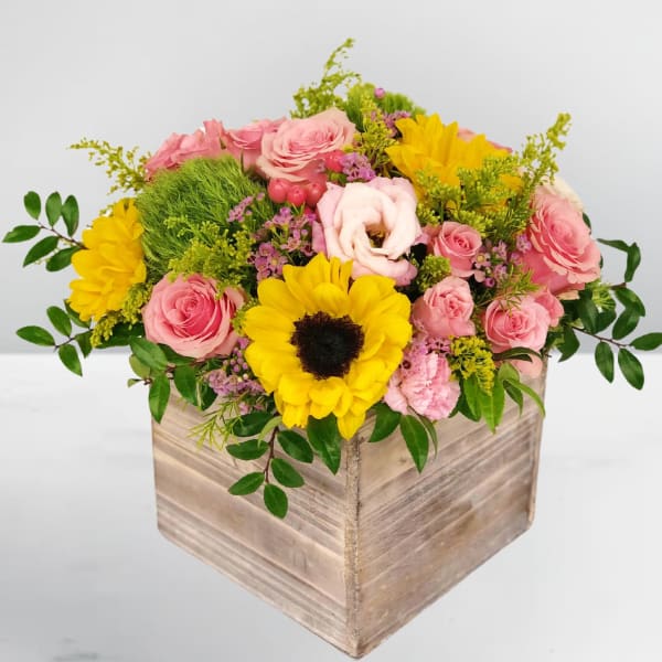 Pink and yellow flower arrangement in a wooden box