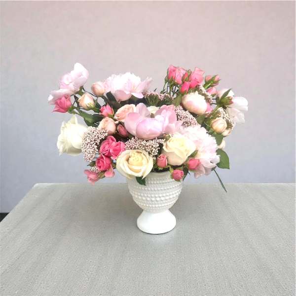 Pink and white rose bouquet in a white pedestal vase